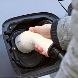 person plugging in a Type 2 charging cable into an electric vehicle's charging port