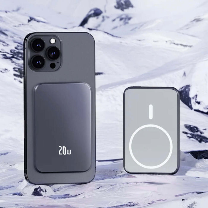 Magsafe Deluxe Powerbank in grey-purple with smartphone, sleek design for stylish charging on snowy mountain backdrop.